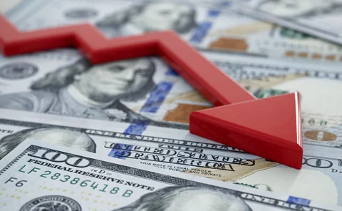 A pile of US dollars beneath a red downward pointing arrow